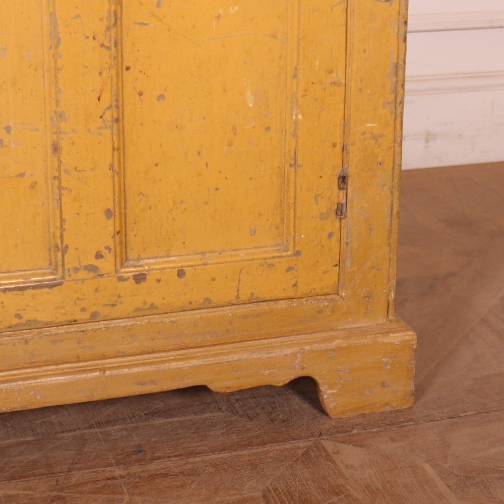 A large antique yellow-painted housekeeper cupboard featuring three upper cupboard doors above an arrangement of drawers and lower cupboards. View VIII