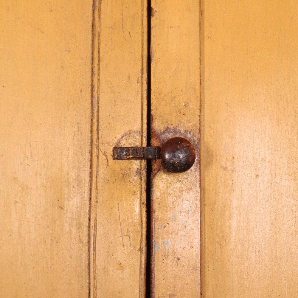 A large antique yellow-painted housekeeper cupboard featuring three upper cupboard doors above an arrangement of drawers and lower cupboards. View IX