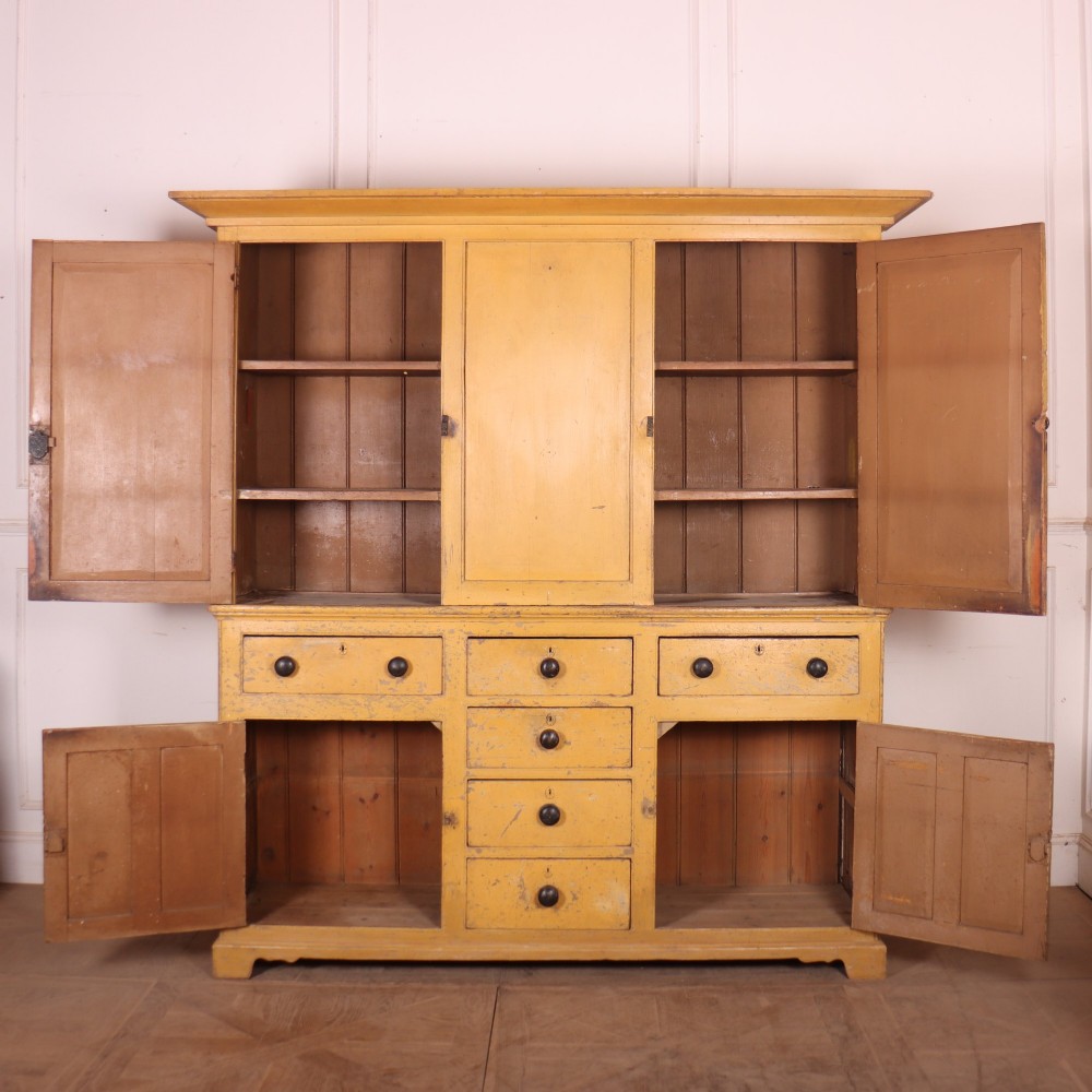 A large antique yellow-painted housekeeper cupboard featuring three upper cupboard doors above an arrangement of drawers and lower cupboards. View XI