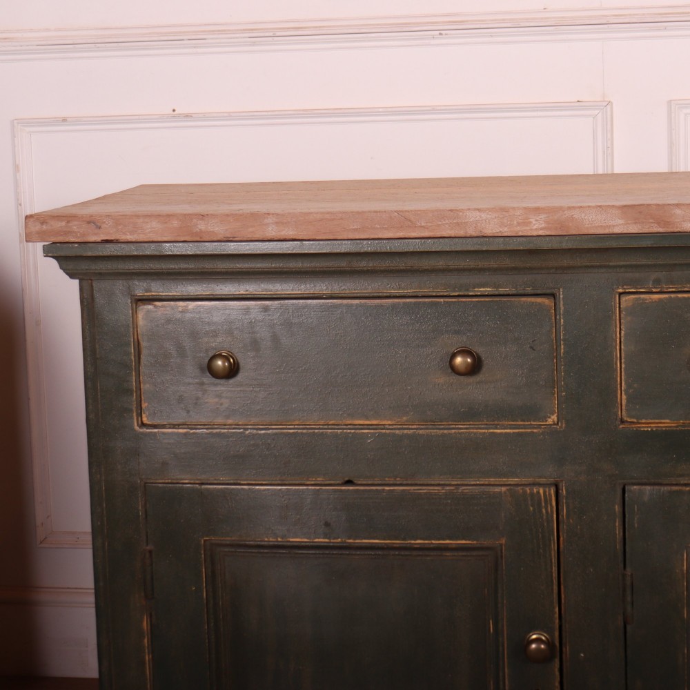 A long dark green painted wooden dresser base featuring four upper drawers over four panelled cupboard doors with a natural timber top. View III