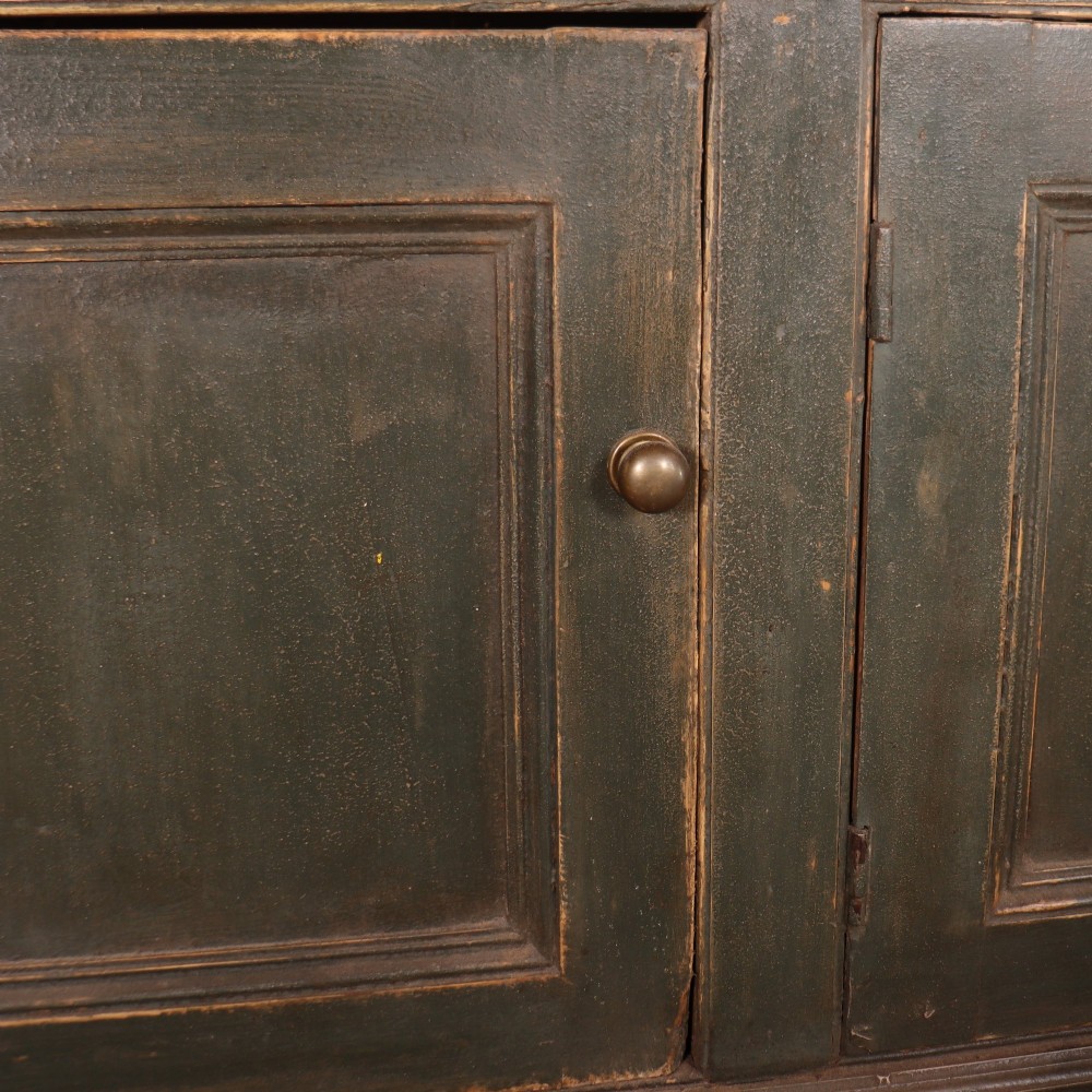 A long dark green painted wooden dresser base featuring four upper drawers over four panelled cupboard doors with a natural timber top. View VI