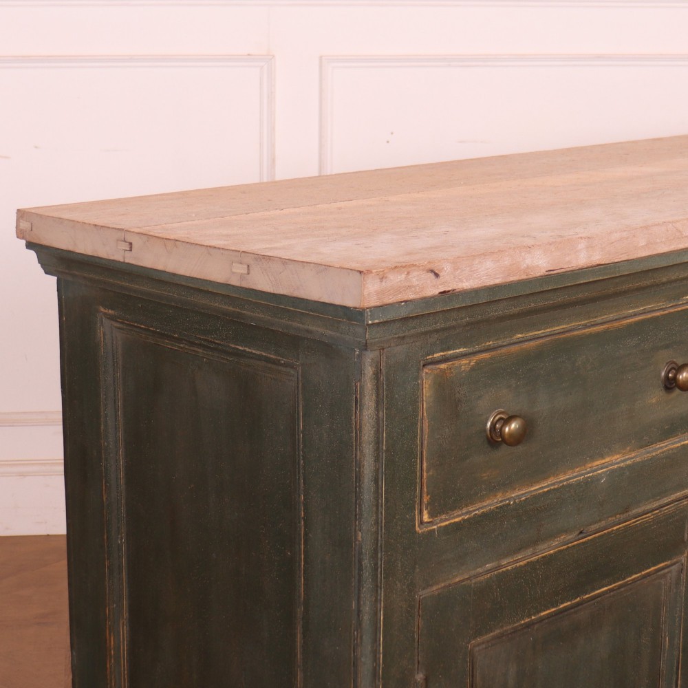 A long dark green painted wooden dresser base featuring four upper drawers over four panelled cupboard doors with a natural timber top. View XII