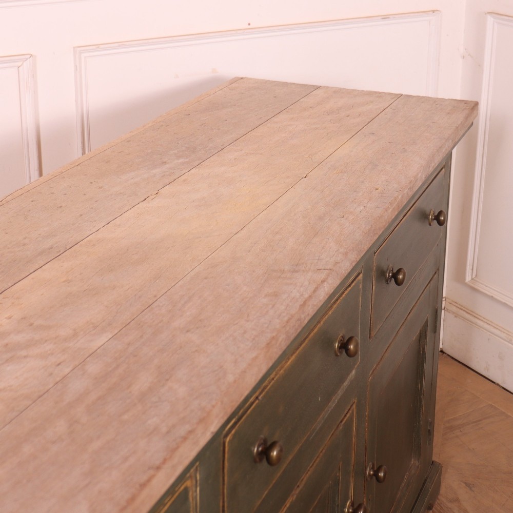 A long dark green painted wooden dresser base featuring four upper drawers over four panelled cupboard doors with a natural timber top. View XIII