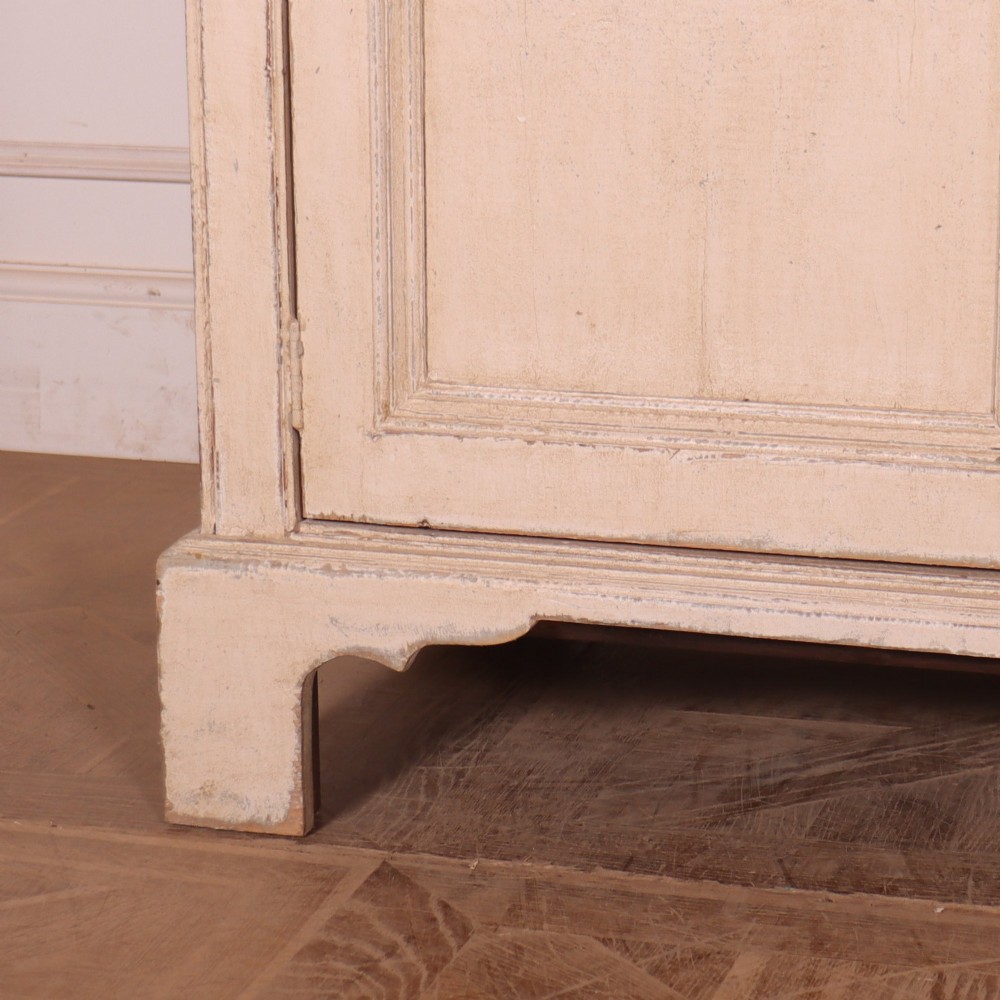 A large off-white painted English dresser base featuring four drawers above four cupboard doors with small brass knob handles. View III