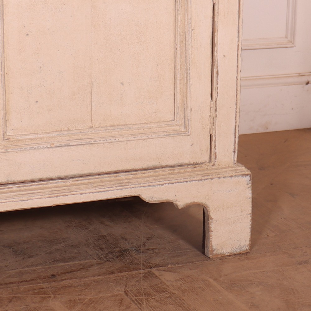 A large off-white painted English dresser base featuring four drawers above four cupboard doors with small brass knob handles. View VI