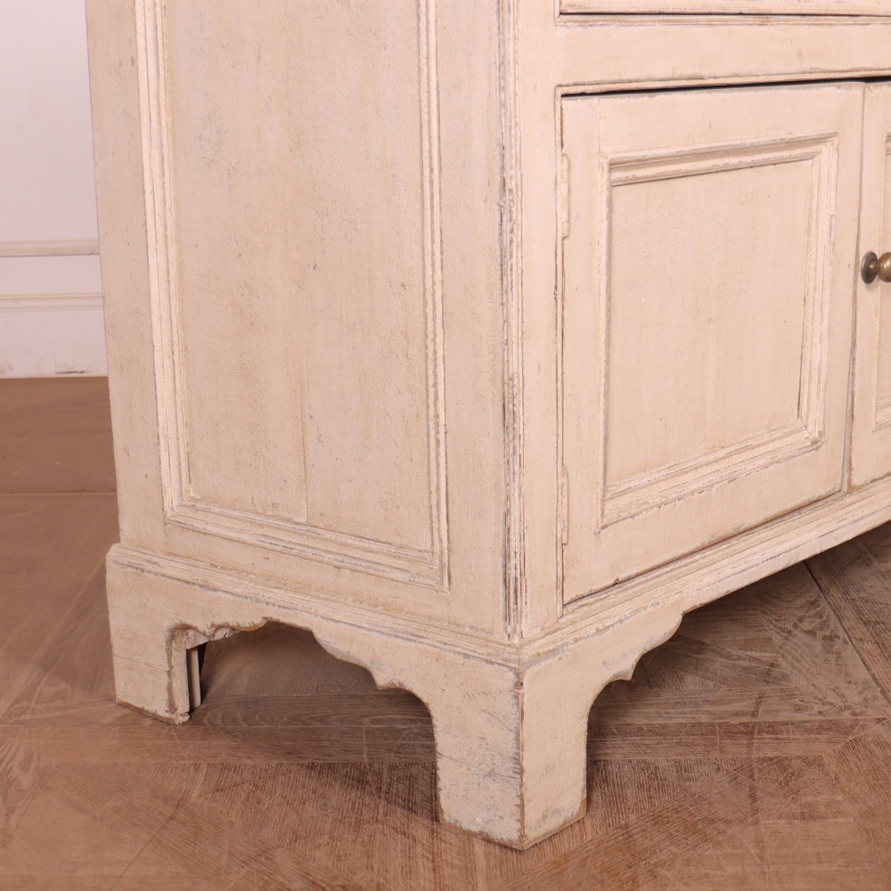 A large off-white painted English dresser base featuring four drawers above four cupboard doors with small brass knob handles. View XI