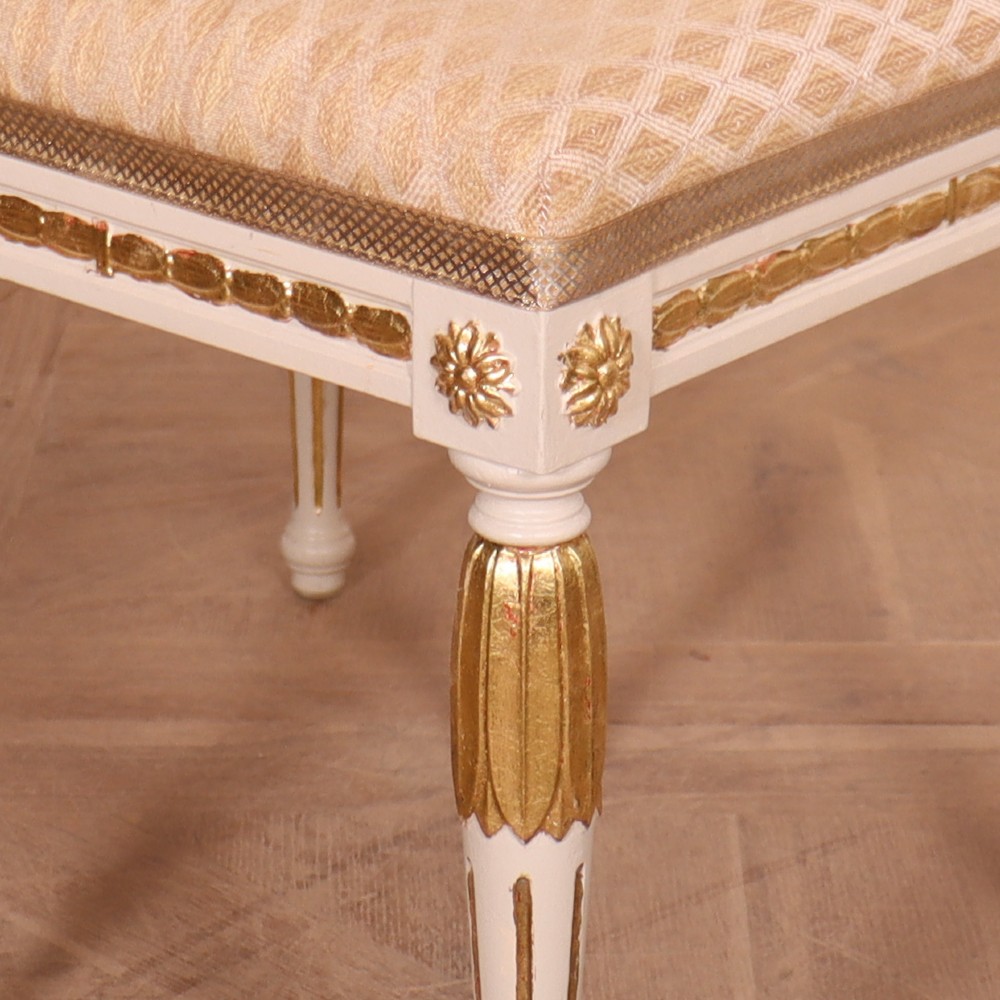 A pair of Neoclassical Swedish Gustavian style footstools with white painted legs, gold leaf fluted details, and cream patterned upholstered seats. View IV