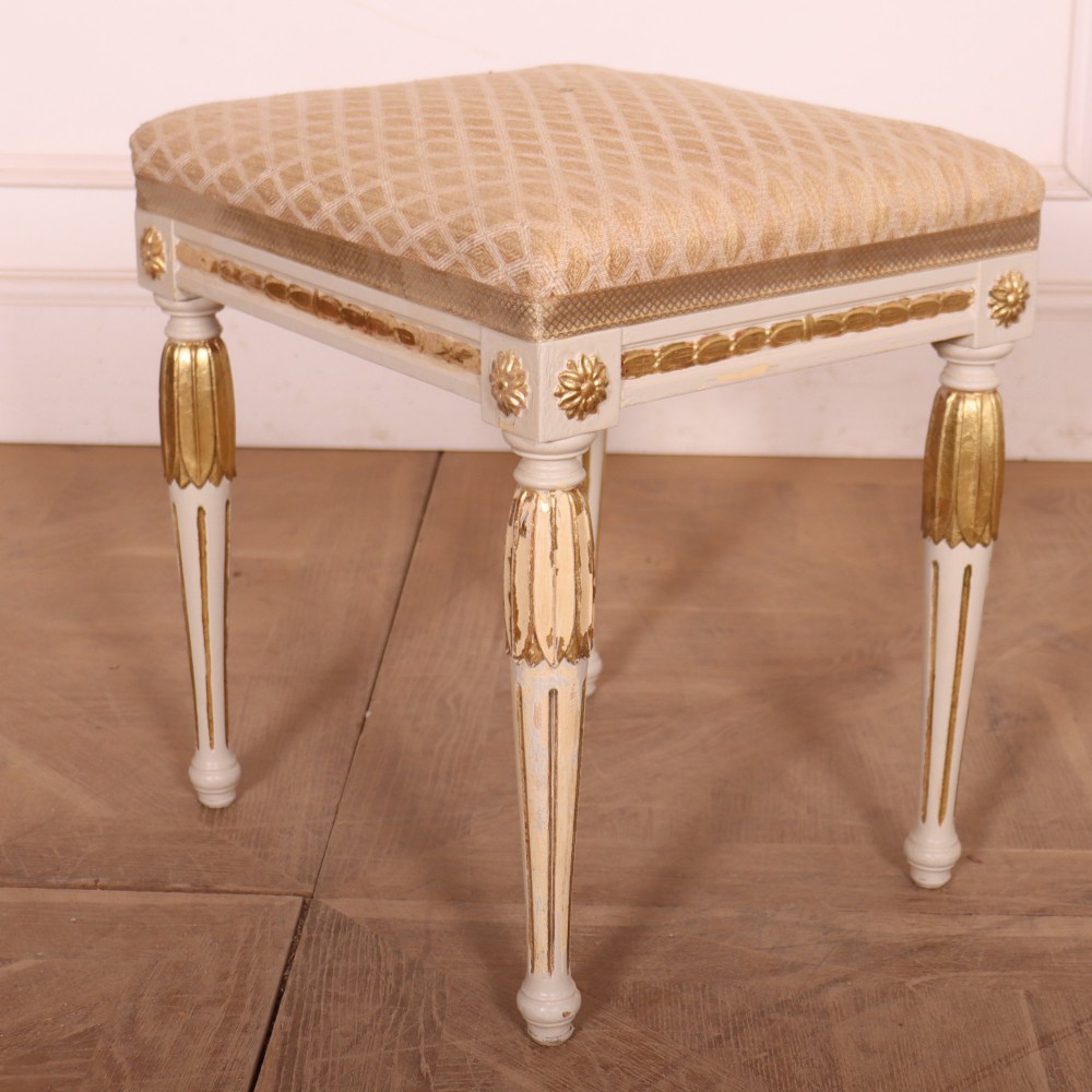 A pair of Neoclassical Swedish Gustavian style footstools with white painted legs, gold leaf fluted details, and cream patterned upholstered seats. View V