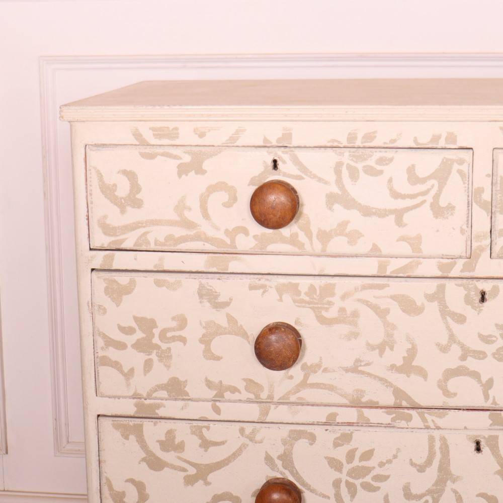 A nineteenth-century cream-painted chest of drawers featuring a beige floral stencil motif across the drawer fronts and turned wooden knobs. View II