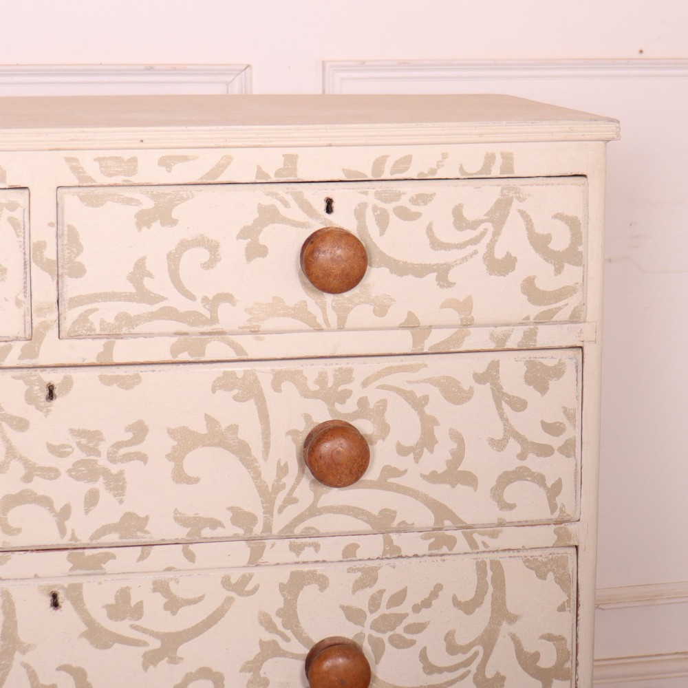A nineteenth-century cream-painted chest of drawers featuring a beige floral stencil motif across the drawer fronts and turned wooden knobs. View III