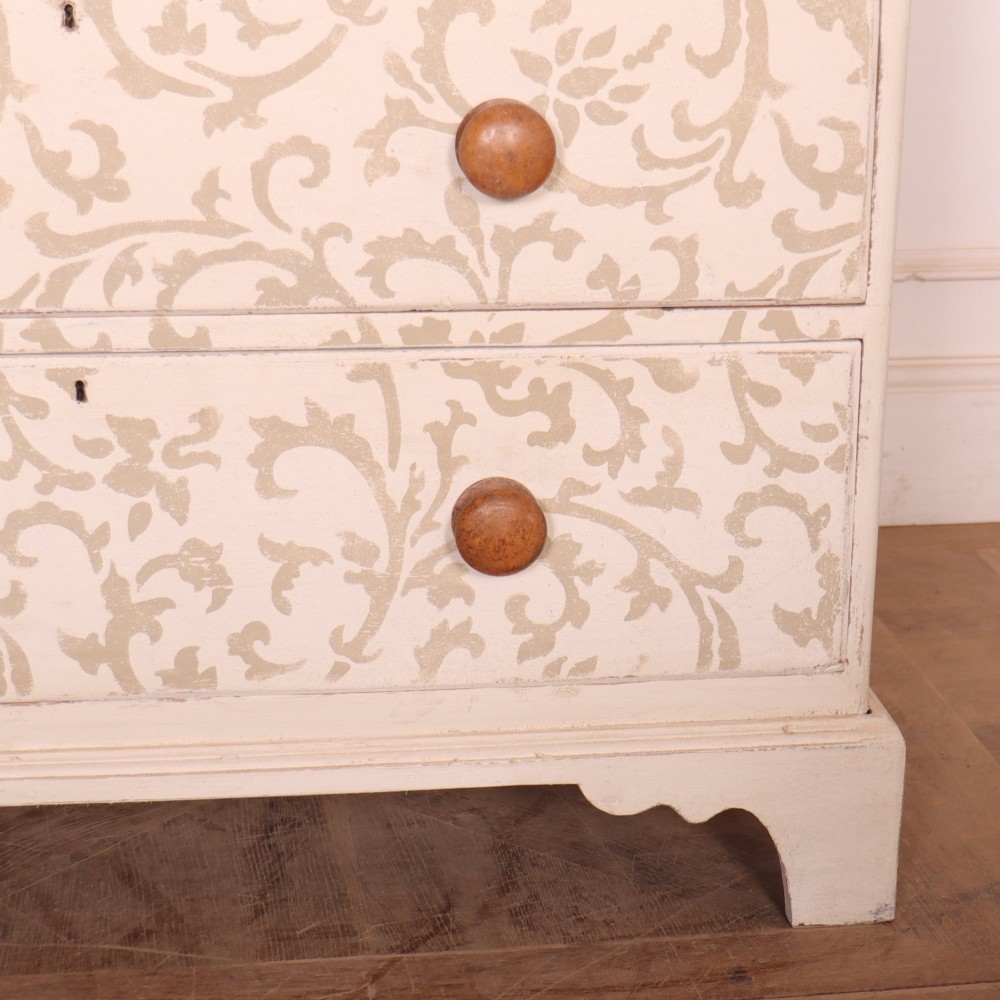 A nineteenth-century cream-painted chest of drawers featuring a beige floral stencil motif across the drawer fronts and turned wooden knobs. View IV