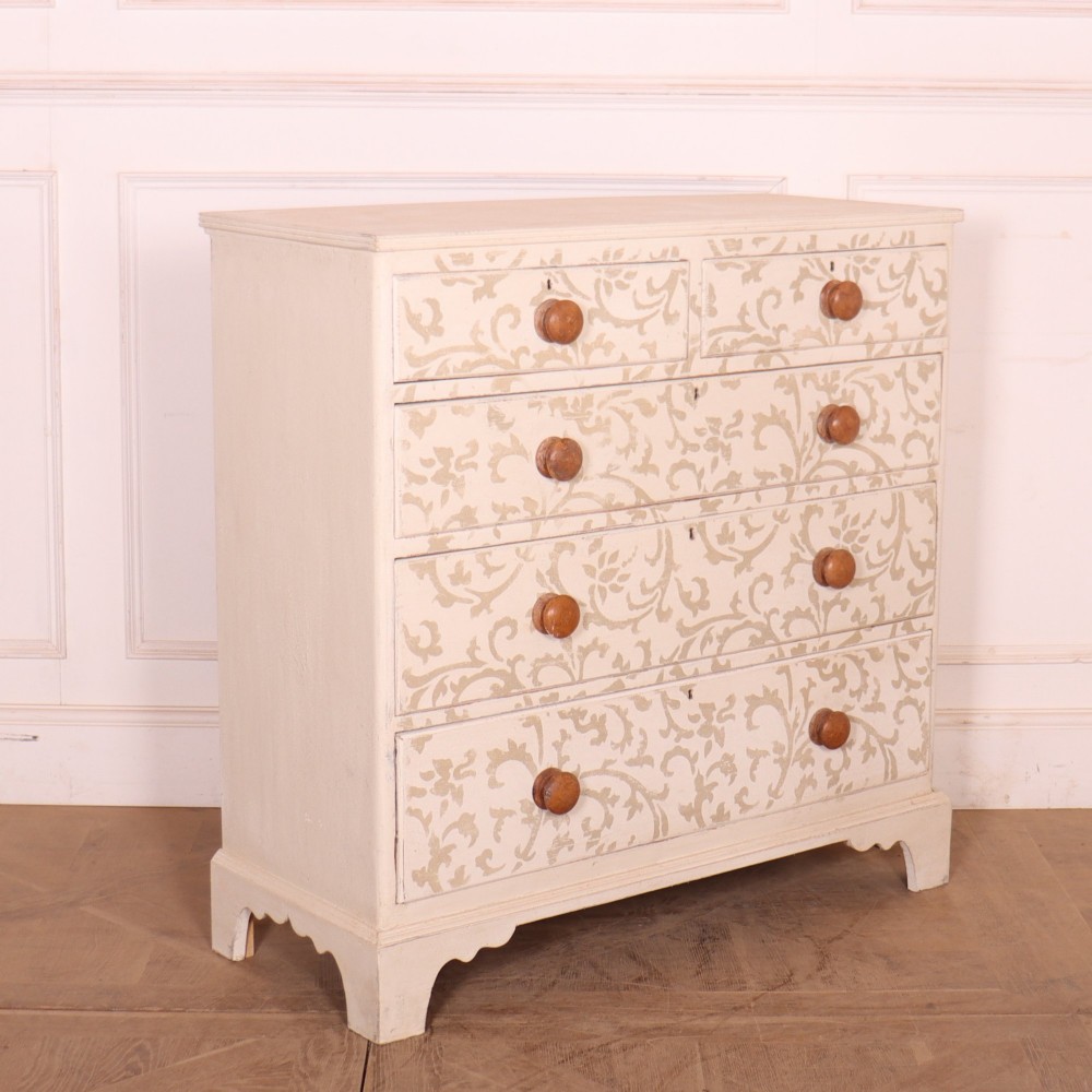 A nineteenth-century cream-painted chest of drawers featuring a beige floral stencil motif across the drawer fronts and turned wooden knobs. View VI