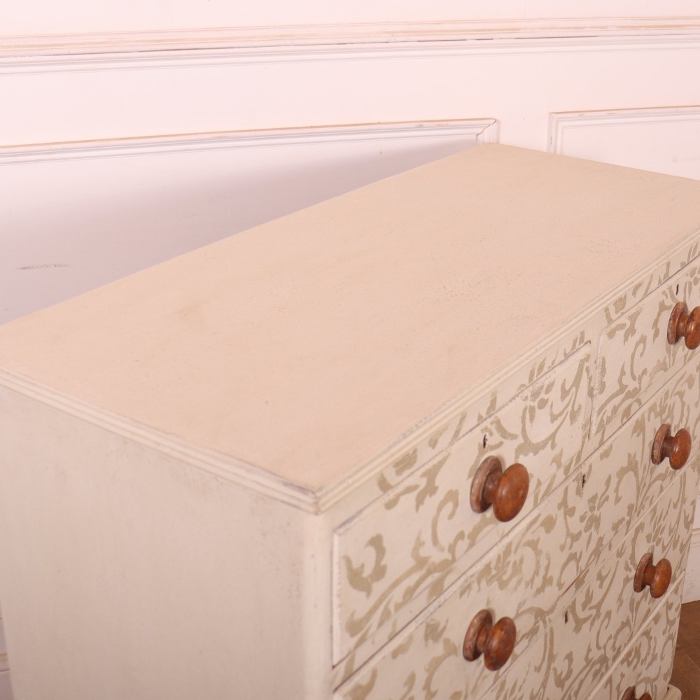 A nineteenth-century cream-painted chest of drawers featuring a beige floral stencil motif across the drawer fronts and turned wooden knobs. View VII