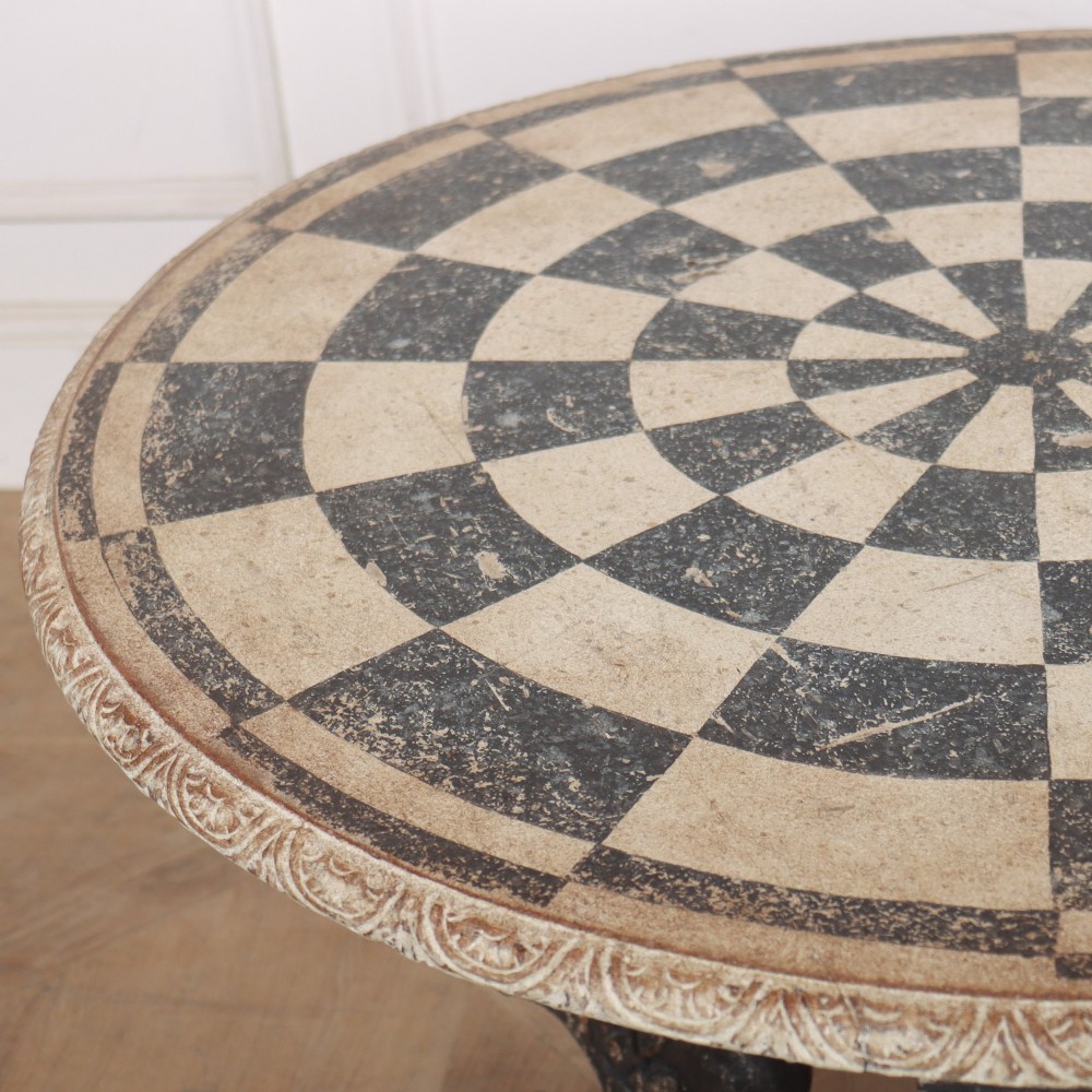 An antique round side table with a cream and grey circular checkerboard top supported by dark carved scroll legs with paw feet. View VI