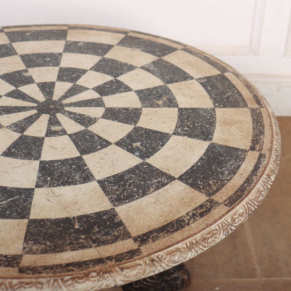 An antique round side table with a cream and grey circular checkerboard top supported by dark carved scroll legs with paw feet. View VII