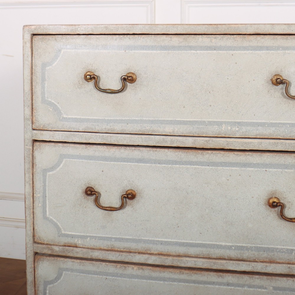 A wide pale grey painted chest featuring six drawers decorated with blue painted border outlines and brass drop handles. View II