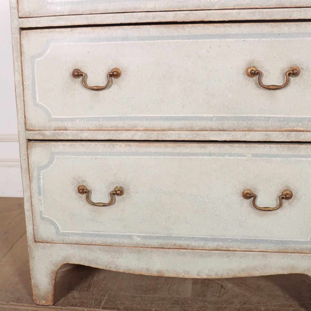 A wide pale grey painted chest featuring six drawers decorated with blue painted border outlines and brass drop handles. View III