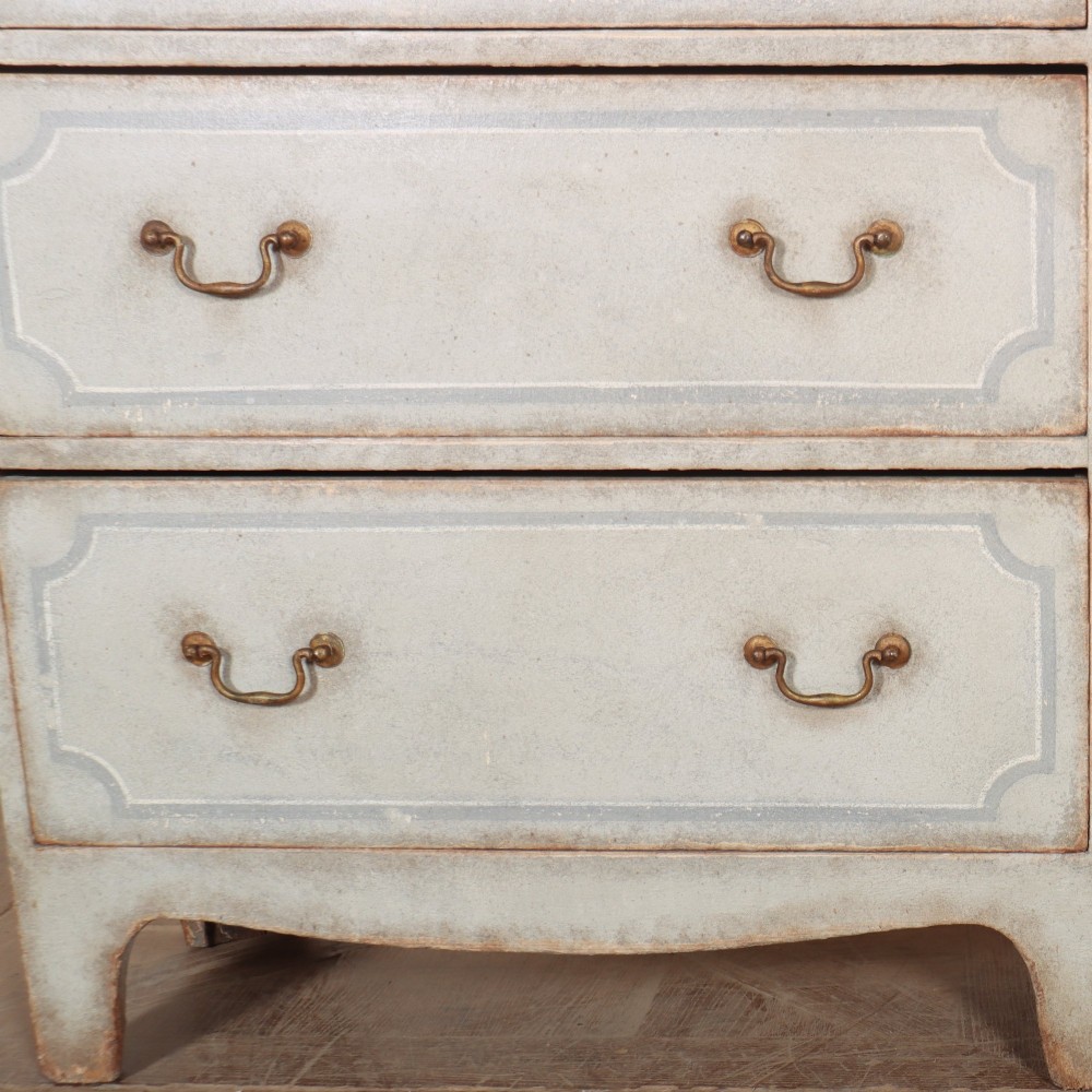 A wide pale grey painted chest featuring six drawers decorated with blue painted border outlines and brass drop handles. View V