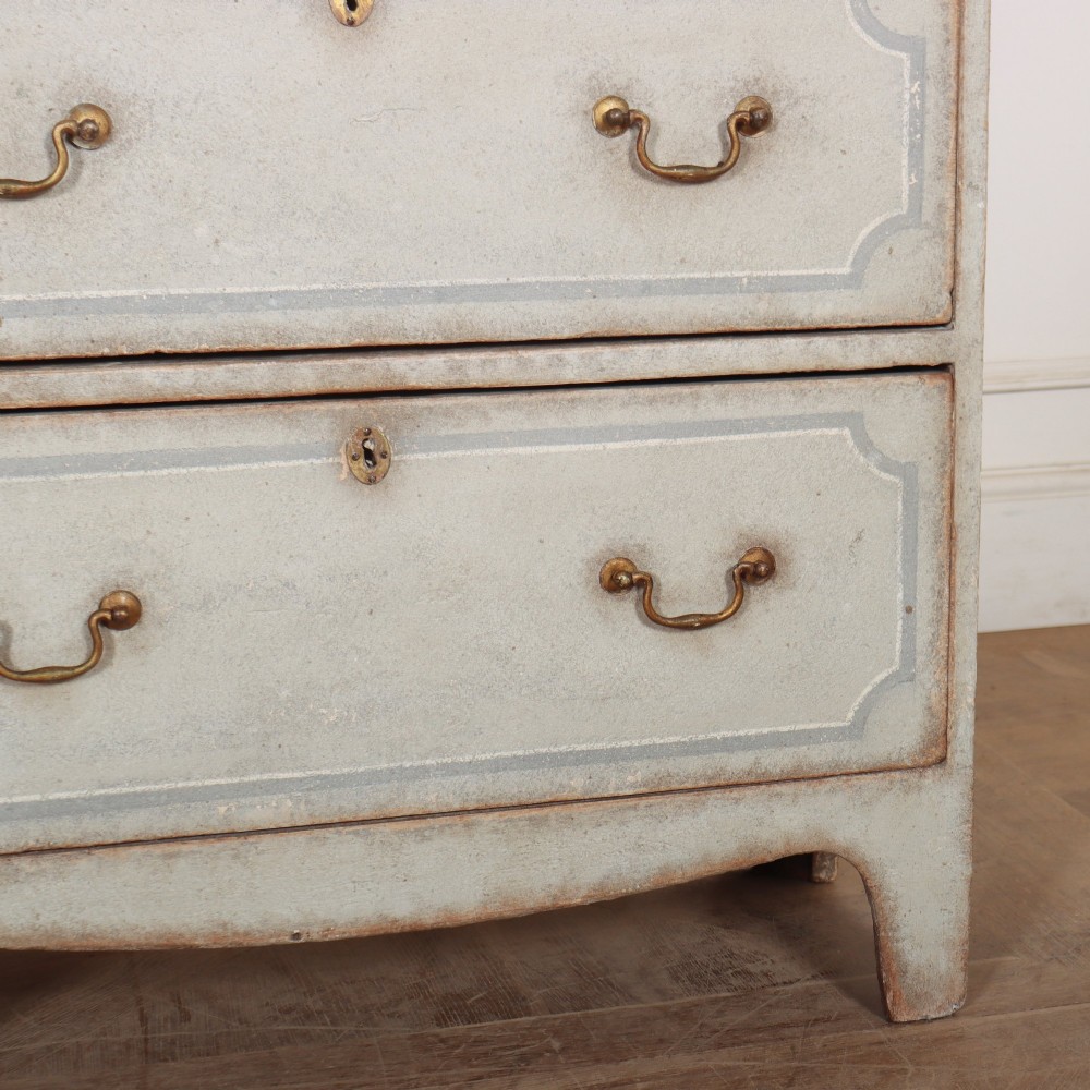 A wide pale grey painted chest featuring six drawers decorated with blue painted border outlines and brass drop handles. View VII