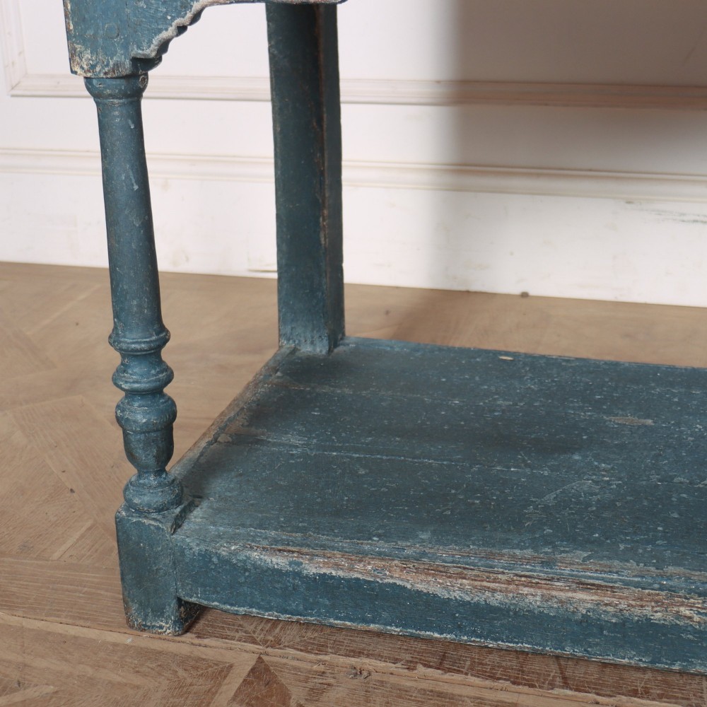 A long blue-painted wooden dresser base featuring three drawers with brass drop handles, a scalloped lower apron, turned front legs, and an open lower potboard shelf. View V