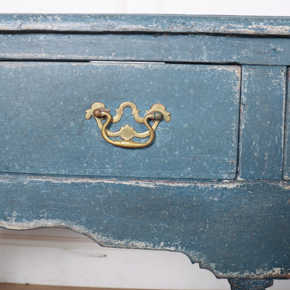 A long blue-painted wooden dresser base featuring three drawers with brass drop handles, a scalloped lower apron, turned front legs, and an open lower potboard shelf. View VIII