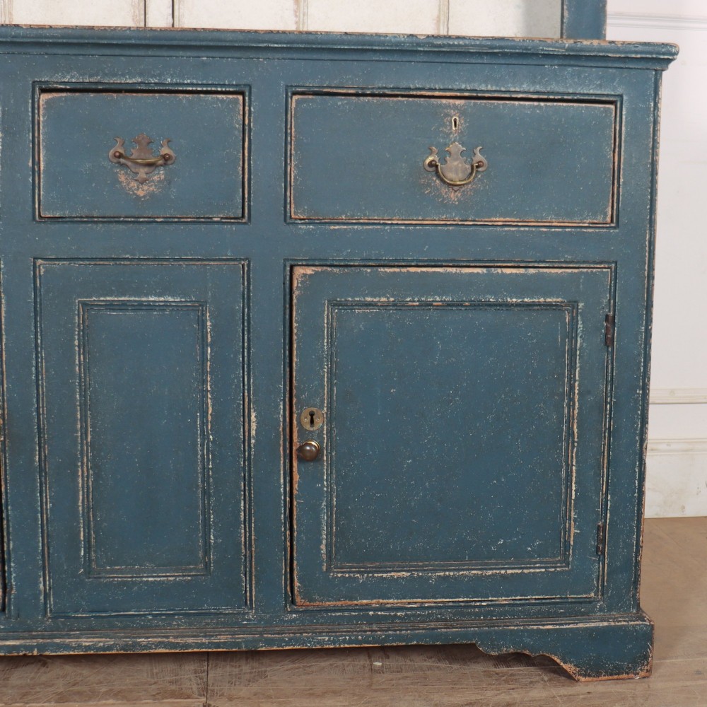 A large dark blue painted antique West Country dresser featuring an open plate rack with off-white backboards above three drawers and three panelled cupboard doors. View VIII