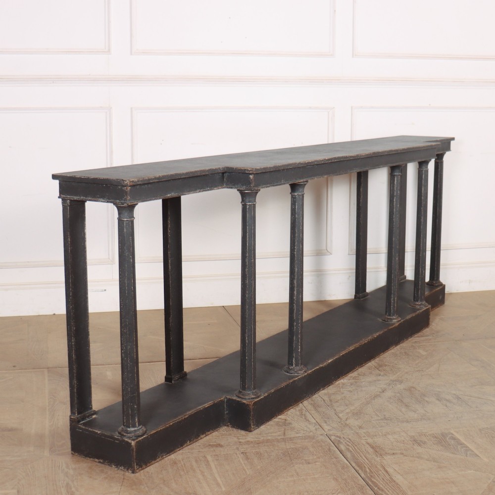 A long black painted beech console table featuring turned column legs and a solid plinth base.