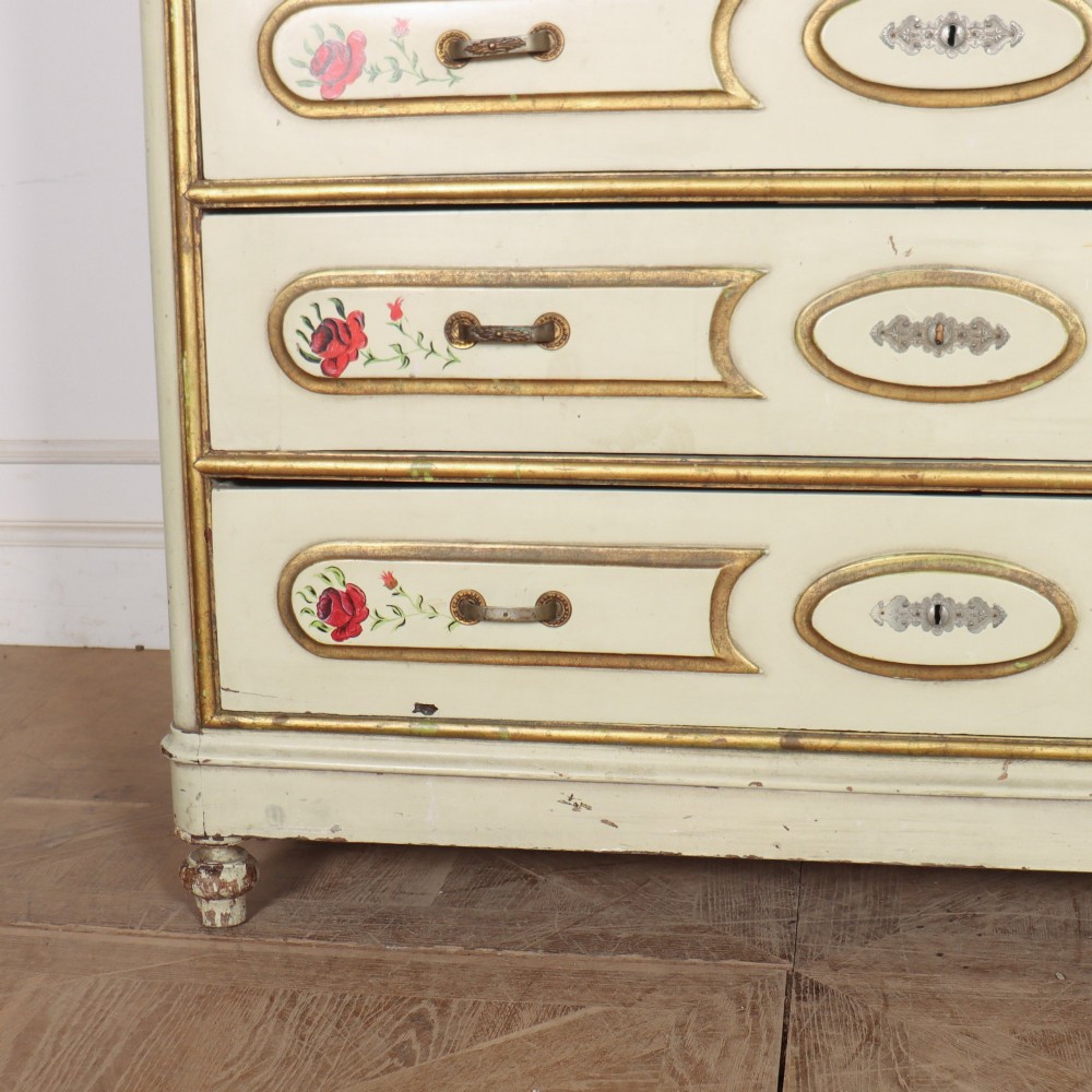 A 19th-century Spanish painted commode in cream featuring hand-painted red floral accents, gilded drawer mouldings, and brass handles. View V