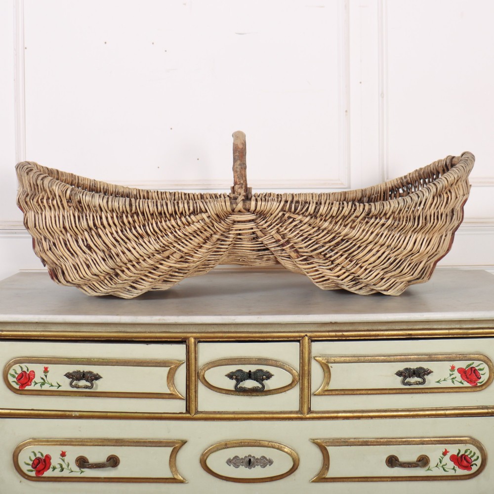 A double-compartment woven wicker grape harvesting basket featuring a central bentwood handle and red painted markings along the woven side. View II