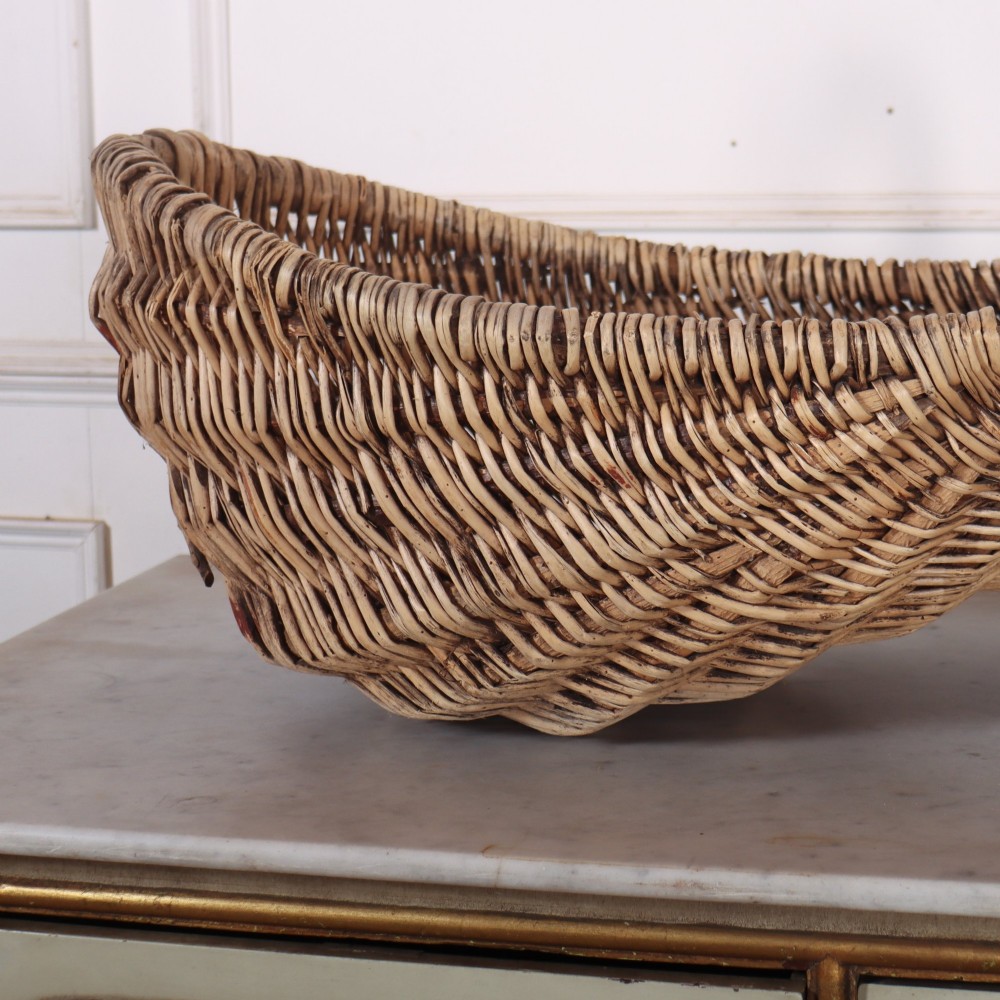A double-compartment woven wicker grape harvesting basket featuring a central bentwood handle and red painted markings along the woven side. View IV