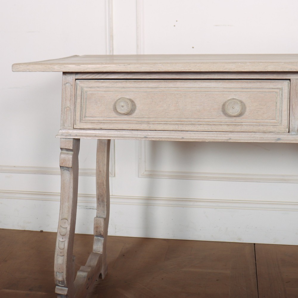 A bleached oak Spanish server table featuring two frieze drawers with round wooden knobs, resting on carved trestle-style end supports. View II