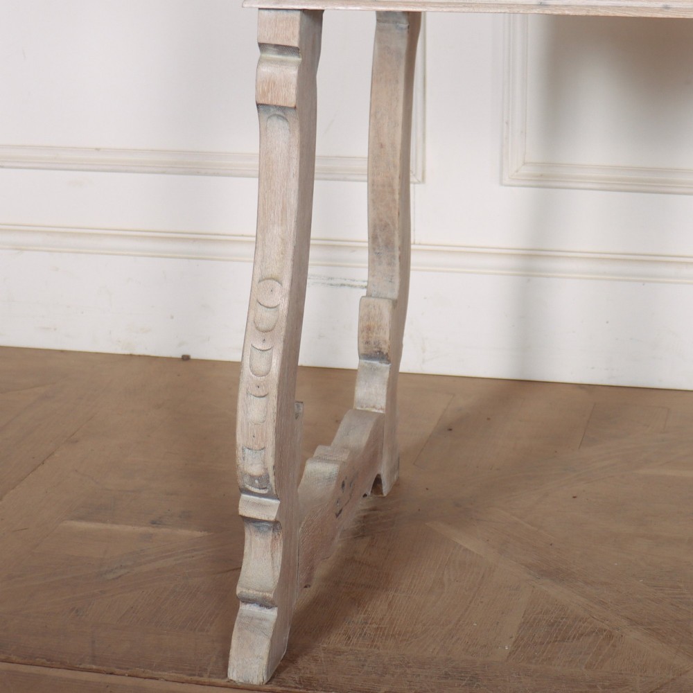 A bleached oak Spanish server table featuring two frieze drawers with round wooden knobs, resting on carved trestle-style end supports. View III