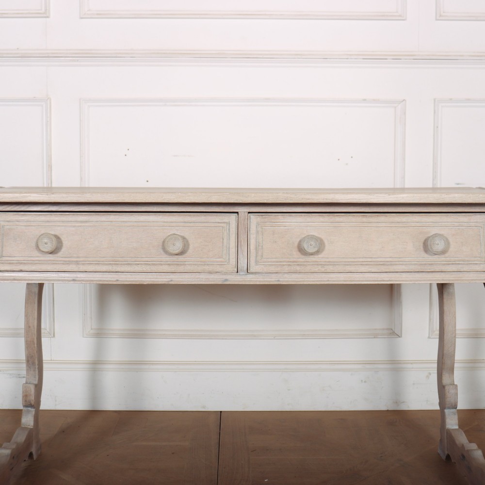 A bleached oak Spanish server table featuring two frieze drawers with round wooden knobs, resting on carved trestle-style end supports. View VI