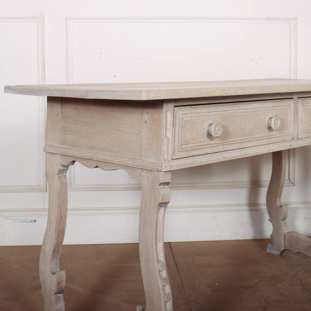 A bleached oak Spanish server table featuring two frieze drawers with round wooden knobs, resting on carved trestle-style end supports. View VIII