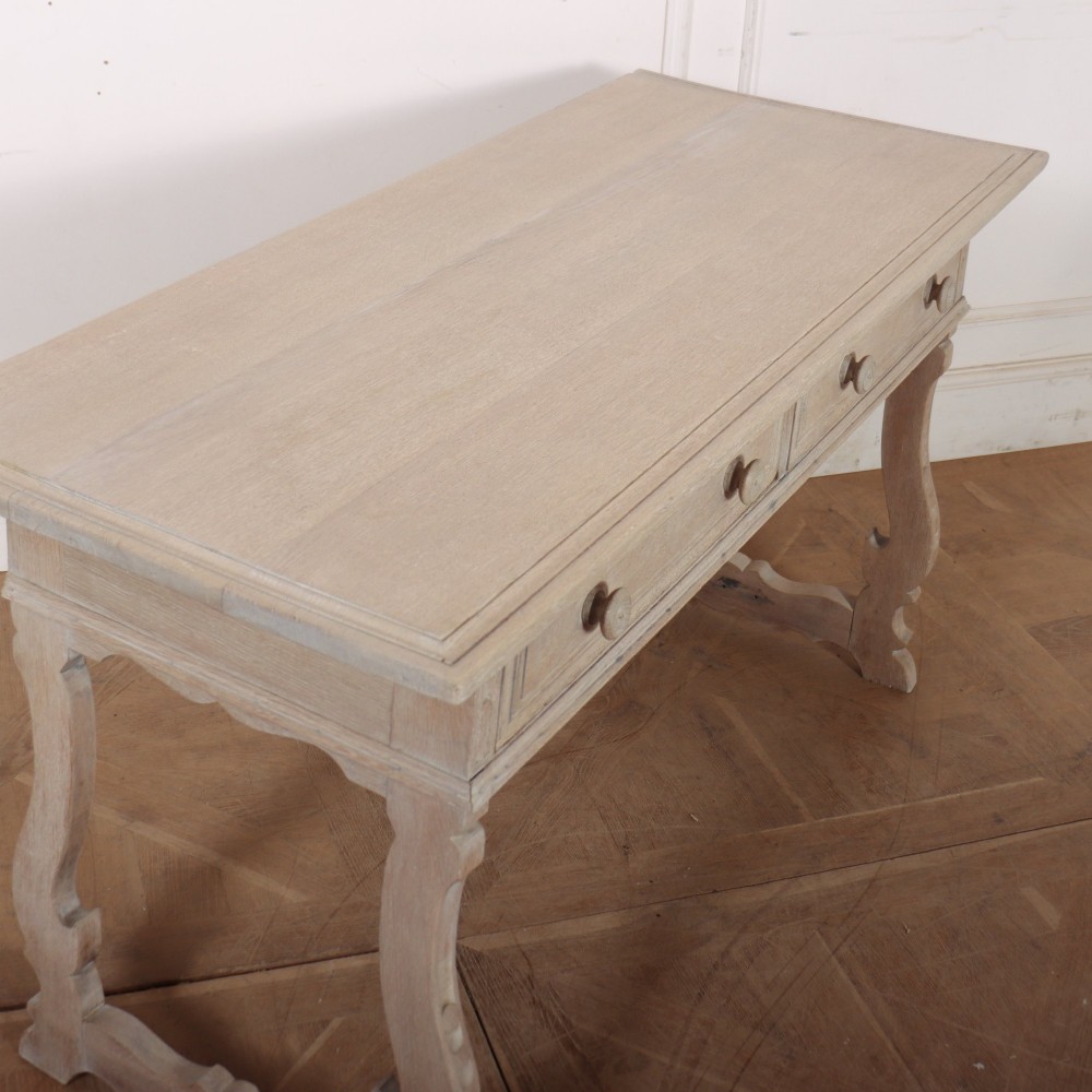 A bleached oak Spanish server table featuring two frieze drawers with round wooden knobs, resting on carved trestle-style end supports. View IX