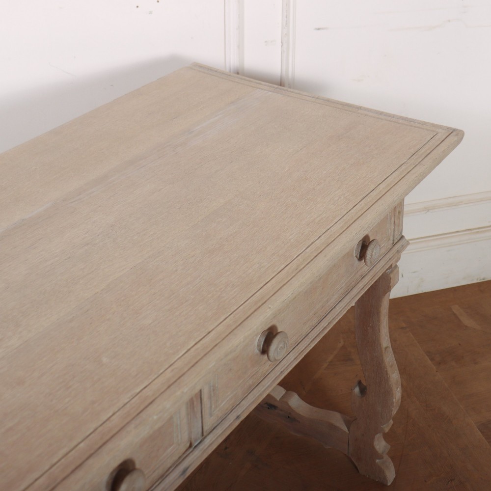 A bleached oak Spanish server table featuring two frieze drawers with round wooden knobs, resting on carved trestle-style end supports. View X