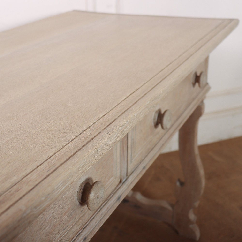 A bleached oak Spanish server table featuring two frieze drawers with round wooden knobs, resting on carved trestle-style end supports. View XI