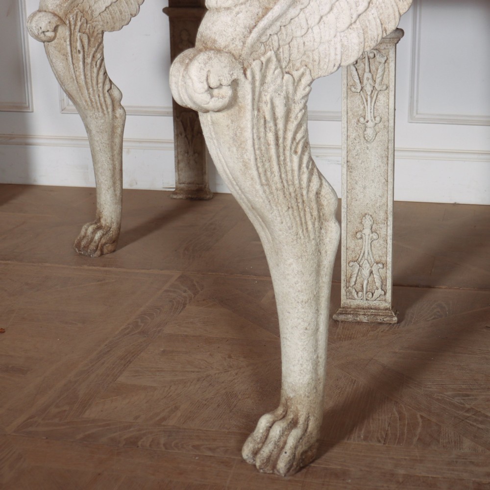 A pair of large off-white painted console tables featuring carved winged lion monopodium supports, anthemion friezes, and dark grey tops. View III