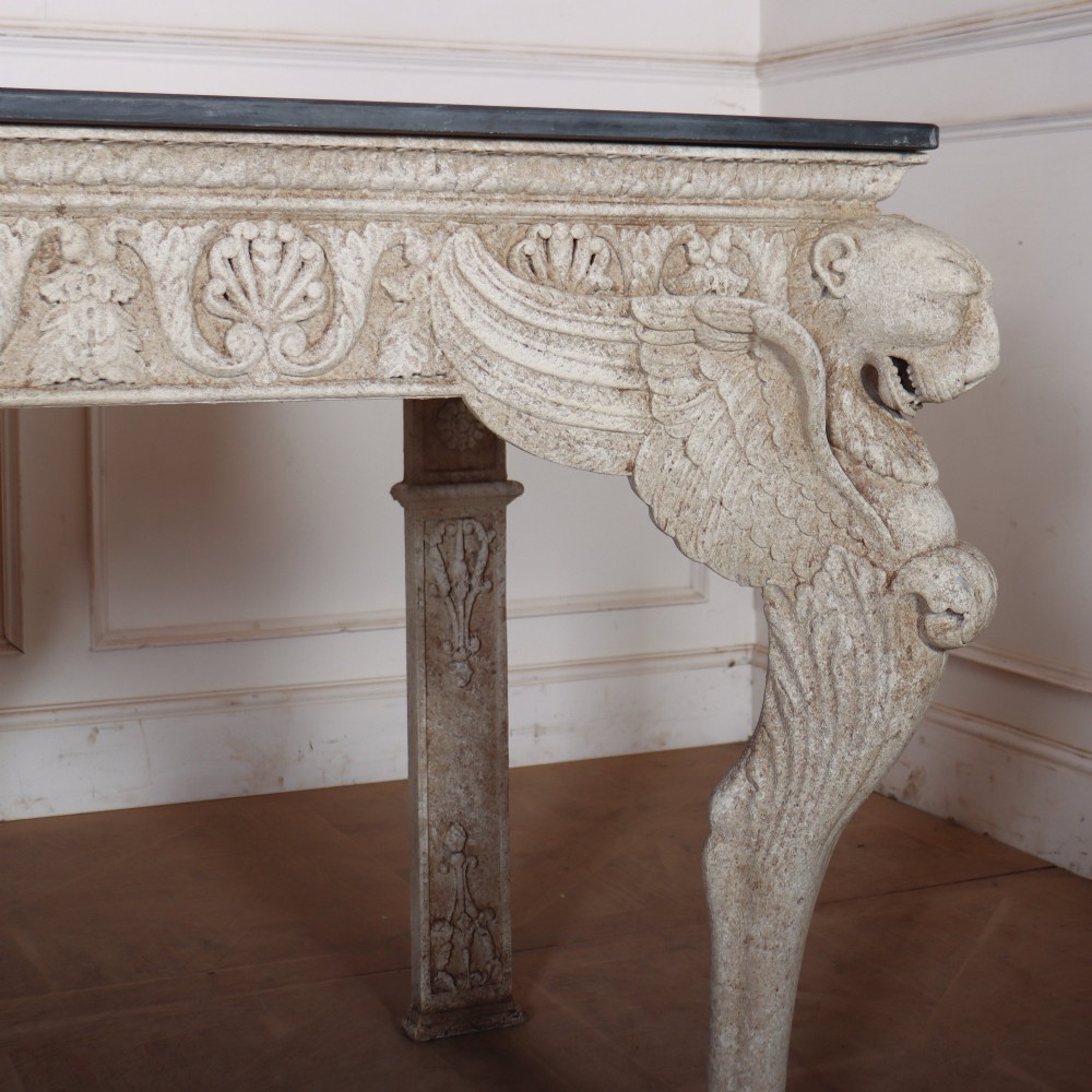 A pair of large off-white painted console tables featuring carved winged lion monopodium supports, anthemion friezes, and dark grey tops. View IV