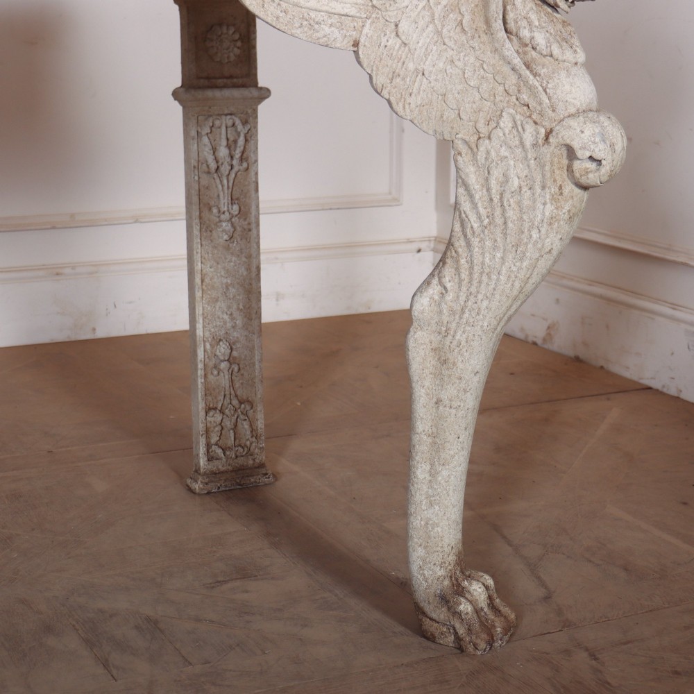 A pair of large off-white painted console tables featuring carved winged lion monopodium supports, anthemion friezes, and dark grey tops. View V