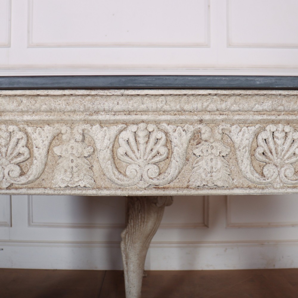A pair of large off-white painted console tables featuring carved winged lion monopodium supports, anthemion friezes, and dark grey tops. View VI