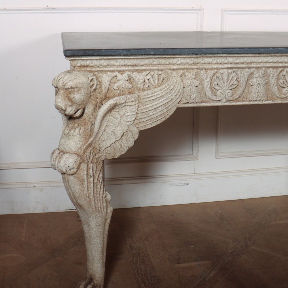 A pair of large off-white painted console tables featuring carved winged lion monopodium supports, anthemion friezes, and dark grey tops. View VIII