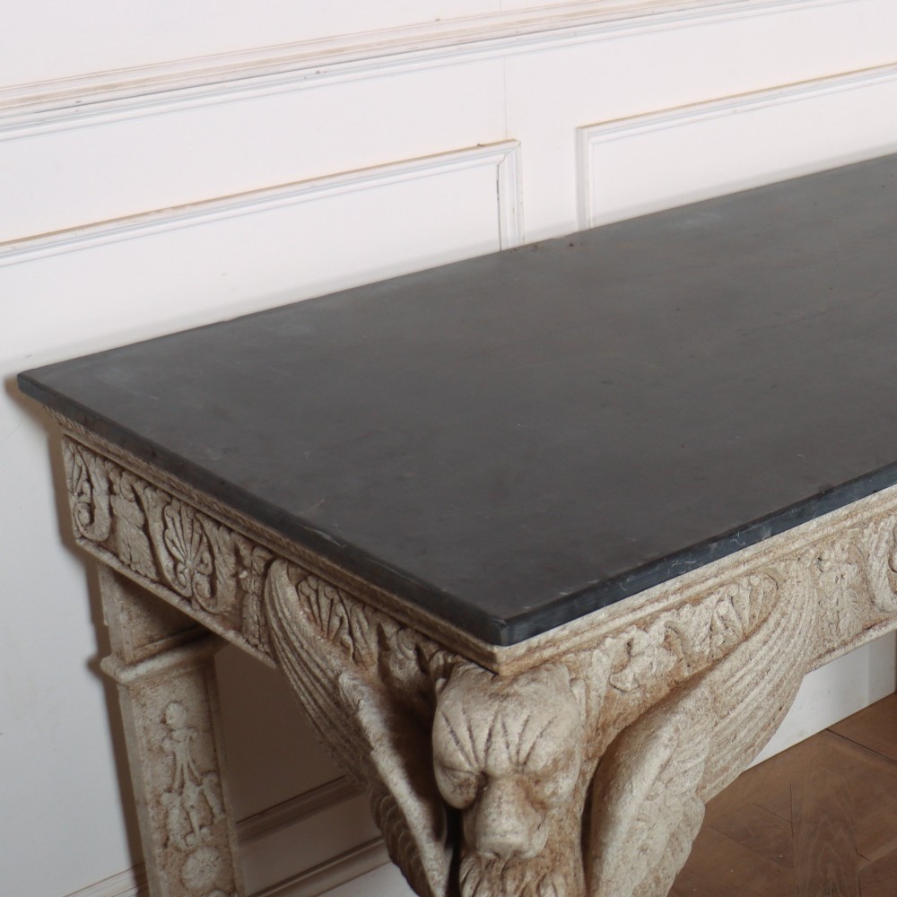 A pair of large off-white painted console tables featuring carved winged lion monopodium supports, anthemion friezes, and dark grey tops. View XII