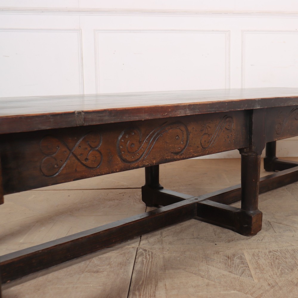 A long, dark oak low coffee table featuring hand-carved frieze panels and square legs joined by a low stretcher base. View III