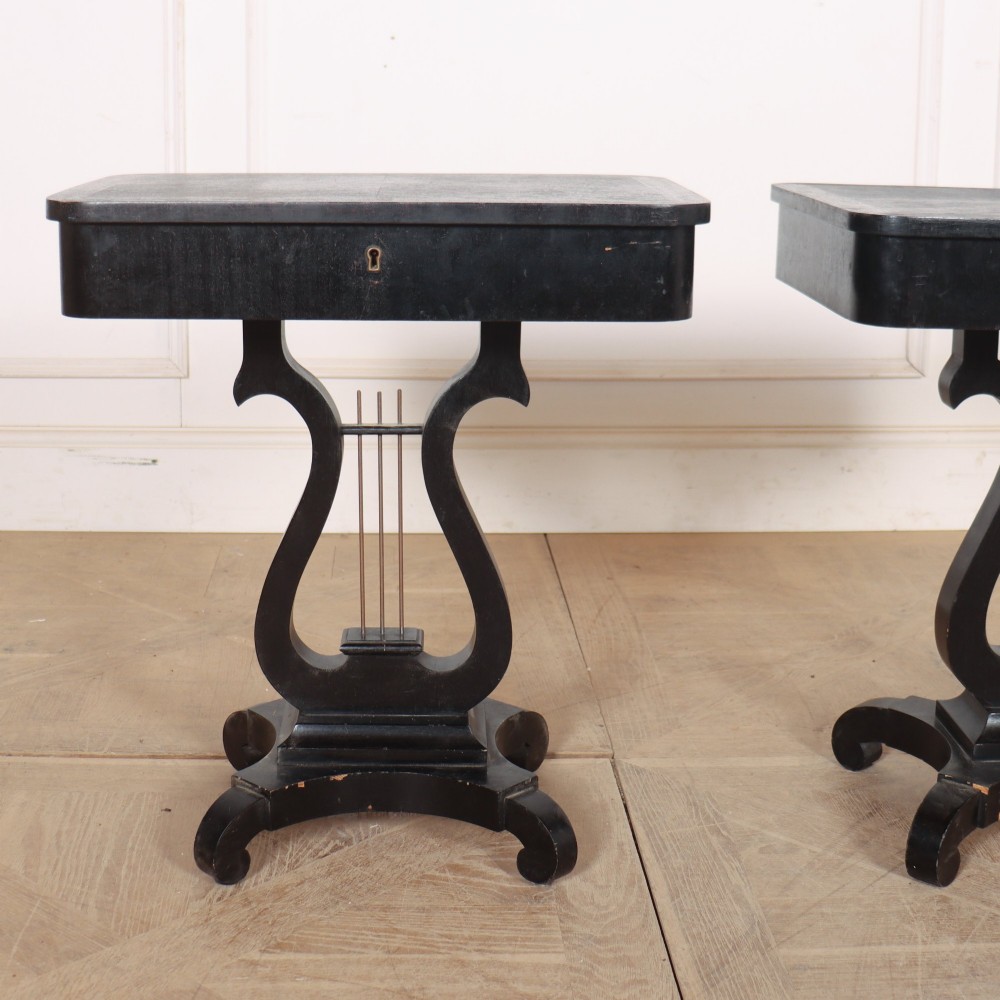 A pair of black ebonised side tables featuring single drawers with brass keyholes and lyre-shaped pedestal bases resting on scroll feet. View II