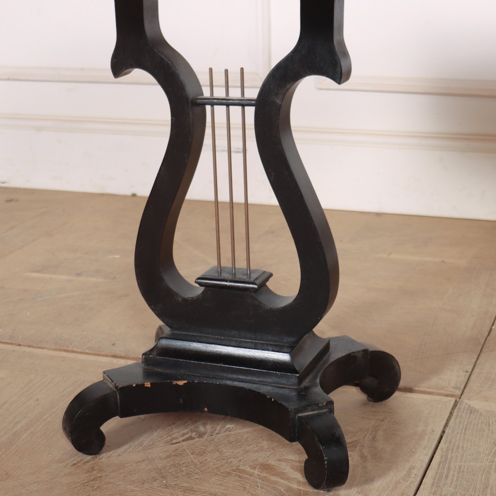 A pair of black ebonised side tables featuring single drawers with brass keyholes and lyre-shaped pedestal bases resting on scroll feet. View IV