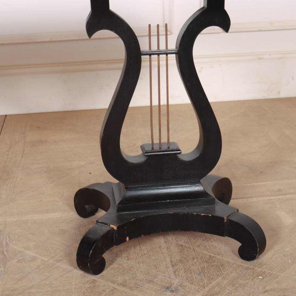 A pair of black ebonised side tables featuring single drawers with brass keyholes and lyre-shaped pedestal bases resting on scroll feet. View V