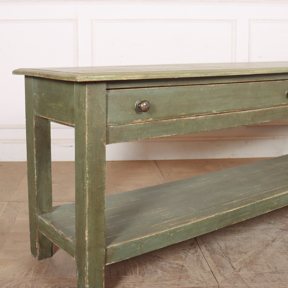 A long, green painted timber potboard serving table featuring two wide drawers with small round knobs and a continuous open shelf below. View II