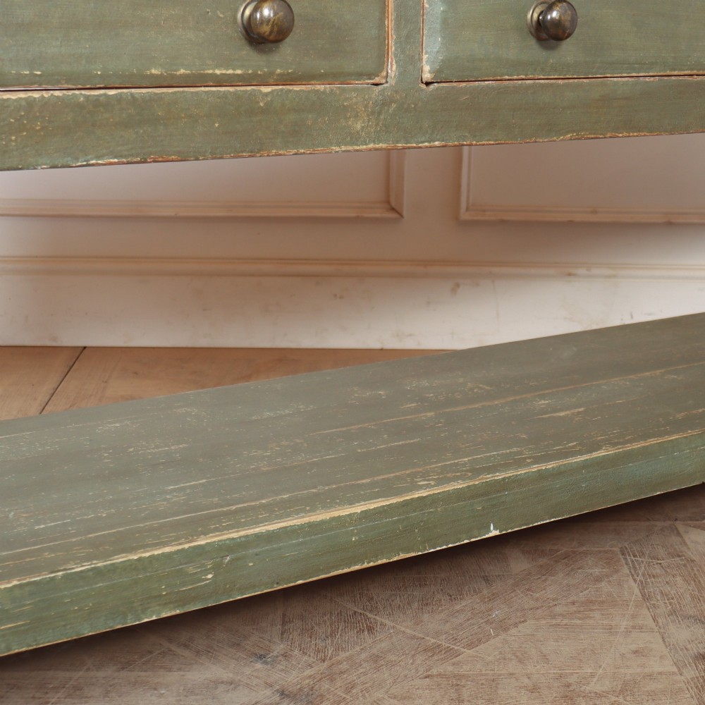 A long, green painted timber potboard serving table featuring two wide drawers with small round knobs and a continuous open shelf below. View V