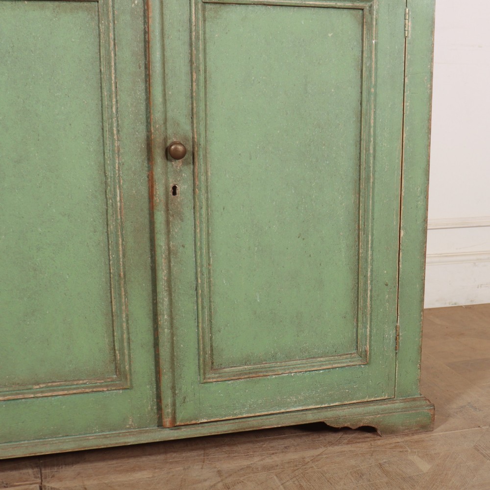 A two-part antique green painted wood kitchen dresser featuring a three-door glazed upper cabinet and three panelled cupboard doors below. View V